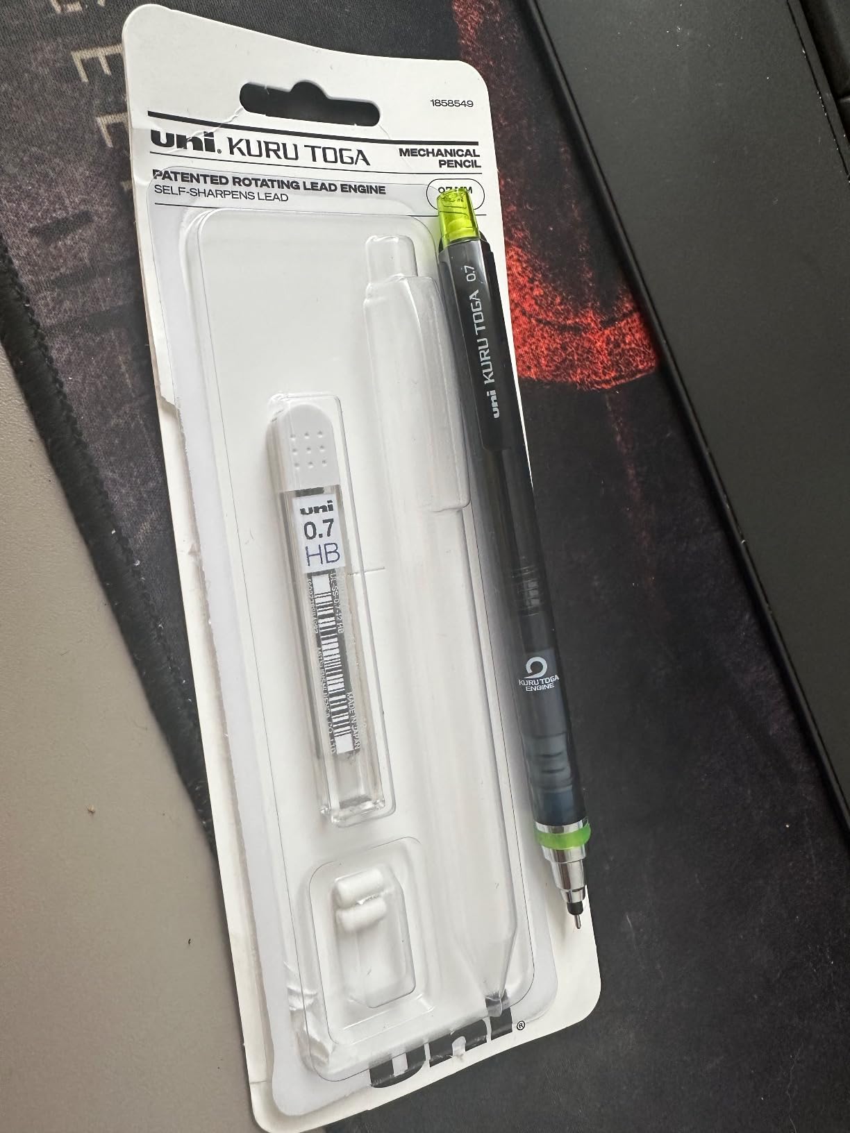Opened uni Kuru Toga 0.7 mm blister pack, item 1858549, on a desk with the smoke-black pencil, its green tip and a tube of 0.7 HB lead