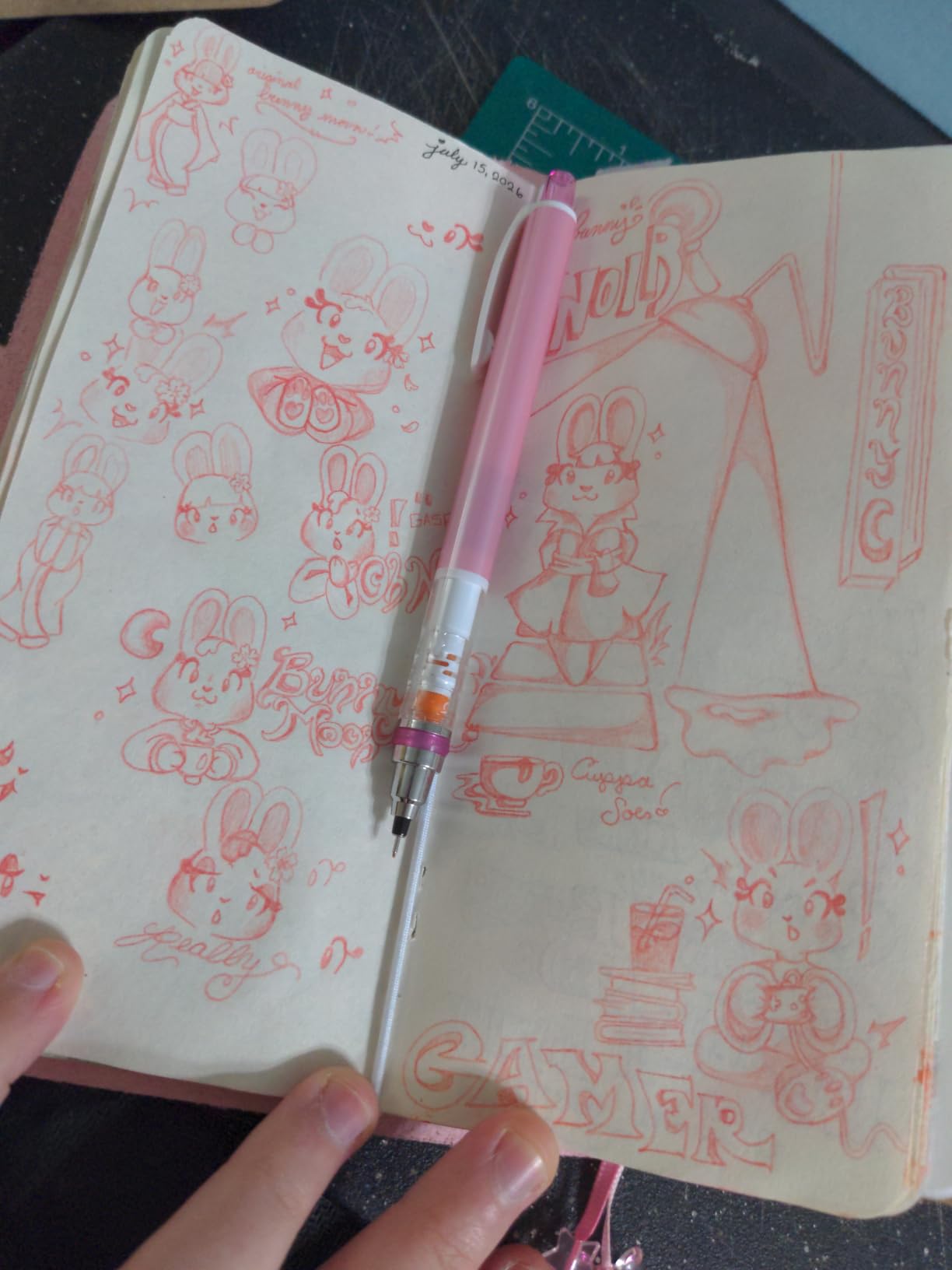 Pink Kuru Toga Standard resting on an open sketchbook filled with bunny doodles drawn in red lead
